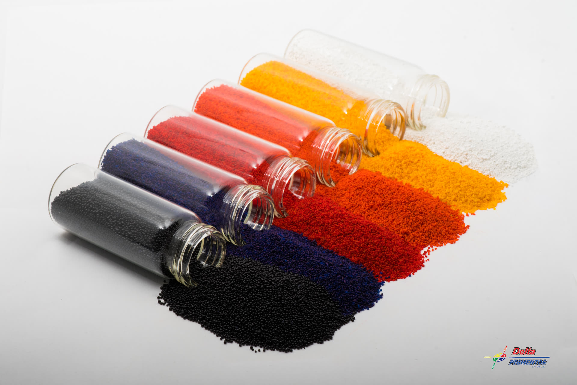 Six Delta masterbatch jars tipped over, with black, blue, red, orange, yellow and white pellets